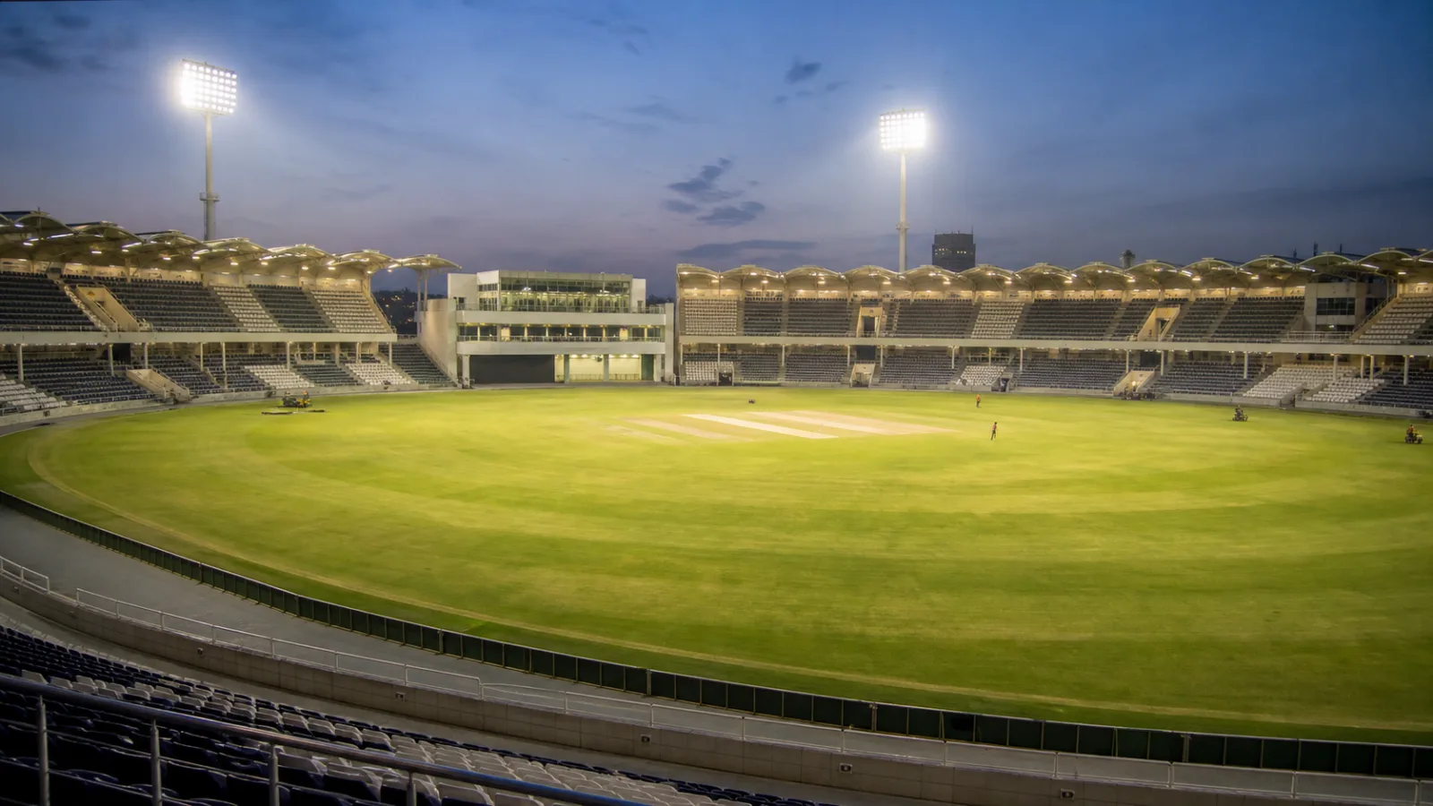 Renovated cricket stadium in Lahore under floodlights with an empty green field and modern curved stands